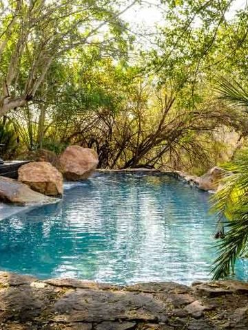 Natürlicher Pool umgeben von Felsen und grünen Bäumen im Freien