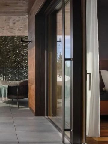 Terrasse mit Blick in Natur und Einblick in modernes Zimmer mit bequemen Bett.