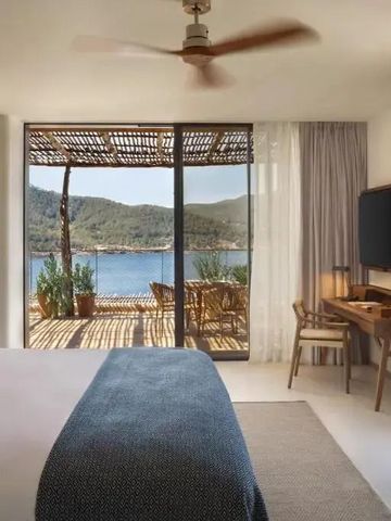 Helles Schlafzimmer mit Deckenventilator und Aussicht auf eine bewaldete Küste