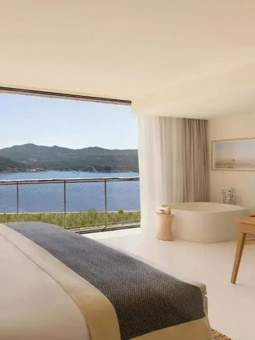 Schlafzimmer mit freistehender Badewanne und Panoramablick aufs Meer