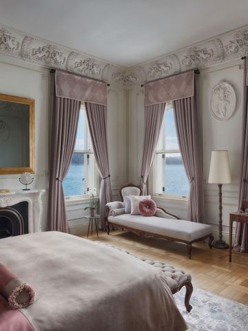Elegantes Schlafzimmer mit dekorativem Kamin und Blick auf das Meer