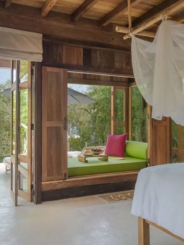 Offenes Schlafzimmer mit grüner Lounge und natürlicher Holzeinrichtung.