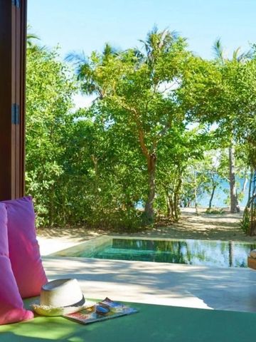 Ausblick von einer Villa mit Sitzbereich und Pool auf tropische Vegetation und das Meer