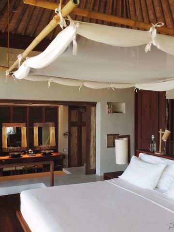 Helles Schlafzimmer mit traditionellem Dach und moderner Einrichtung bei Six Senses Samui
