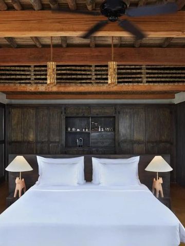 Luxuriöses Schlafzimmer mit Holzbalkendecke und dekorativen Lampen