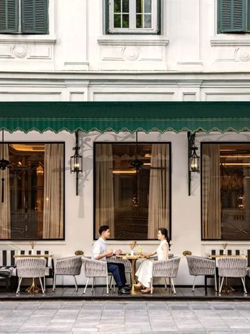 Paar sitzt im stilvollen Außenbereich eines Cafés mit klassischer Fassade