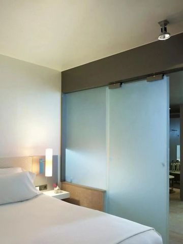 Modernes Hotelzimmer mit einem großen Bett und Glastrennwand.