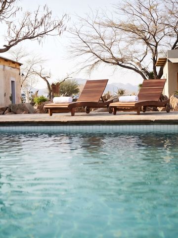 Poolbereich mit Liegestühlen umgeben von Bäumen