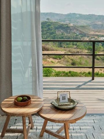 Terrasse mit Blick auf grüne Hügel. Moderne Holzmöbel und elegante Gestaltung.