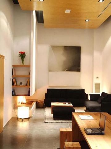 Moderne Lounge mit schwarzen Sofas und Kamin in heller Umgebung