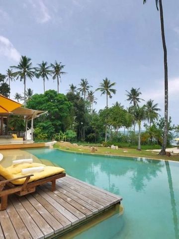 Infinity-Pool mit Blick auf den Strand und umgeben von tropischen Bäumen