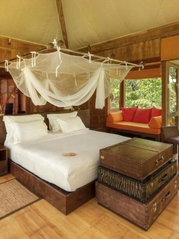 Geräumiges Schlafzimmer mit Himmelbett und natürlichem Ambiente im Soneva Kiri