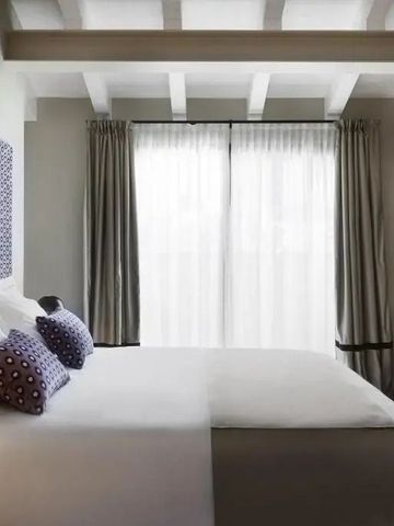 Modernes Doppelzimmer mit großen Fenstern und Holzbalkendecke