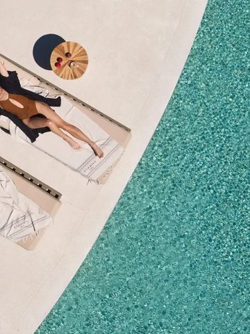Frau entspannt sich am Pool neben klarem, türkisfarbenem Wasser