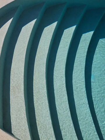 Stufen führen in einen türkisblauen Pool mit klarem Wasser