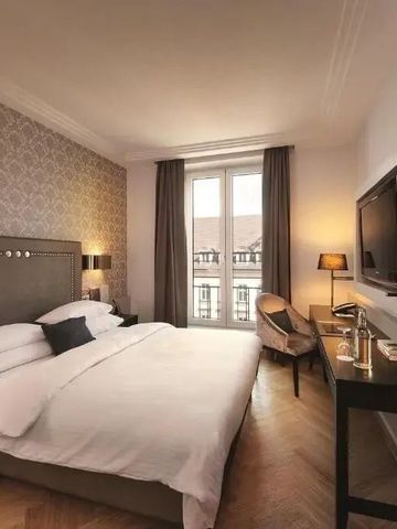Elegantes Hotelzimmer mit Doppelbett und Schreibtisch neben großen Fenstern