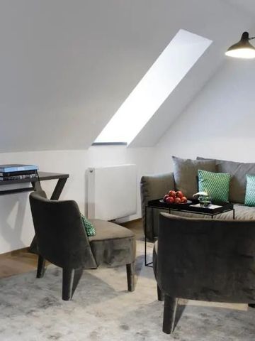 Wohnbereich mit Sofa und Sesseln unter Dachschräge