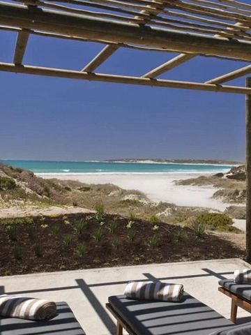 Terasse mit Sonnenliegen und Blick auf den weißen Sandstrand