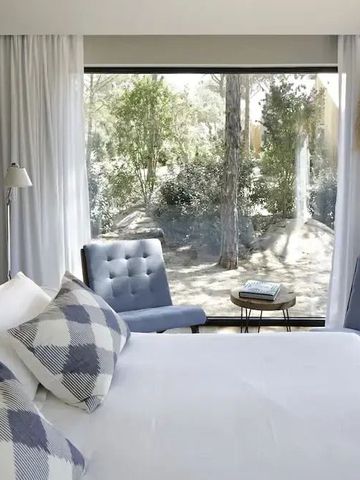 Helles Schlafzimmer mit bequemen Sesseln und Blick auf die Natur