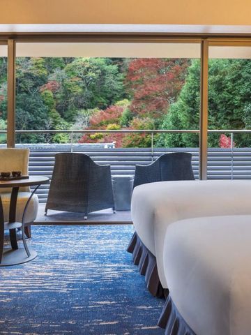 Geräumiges Hotelzimmer mit Balkon und Blick auf bunte Herbstbäume