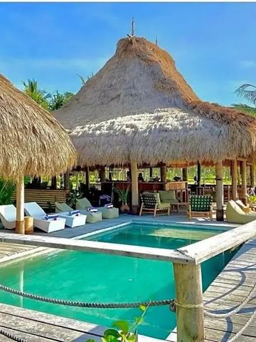 Charmante Poollandschaft mit Liegen und strohgedecktem Pavillon im Sumba Beach House