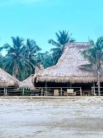 Strandbungalow mit Palmen und strohgedecktem Dach am Sumba Beach