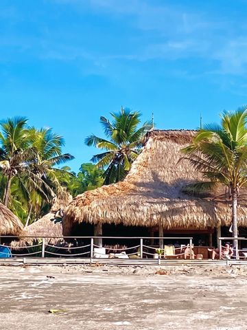 Traditionell strohgedeckte Strandbar im tropischen Ambiente mit Palmen.