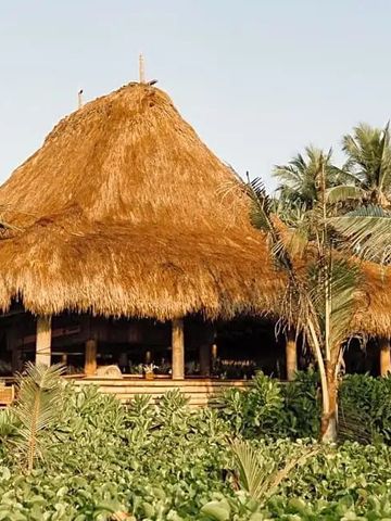 Strohgedecktes Restaurant eingebettet in üppige, tropische Vegetation.