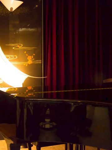 Klaviertastatur bei schummrigem Licht mit rotem Vorhang im Hintergrund.