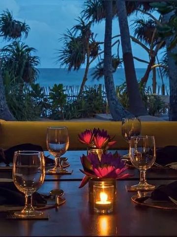 Romantisch gedeckter Tisch mit Blick auf den Strand und Palmen bei Sonnenuntergang