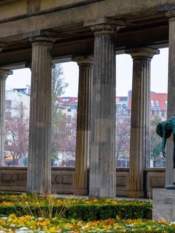 Historische Säulengalerie mit Park und Statue im Hintergrund