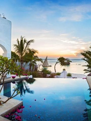 Infinity-Pool mit Blick auf den Ozean bei Sonnenuntergang umgeben von Palmen