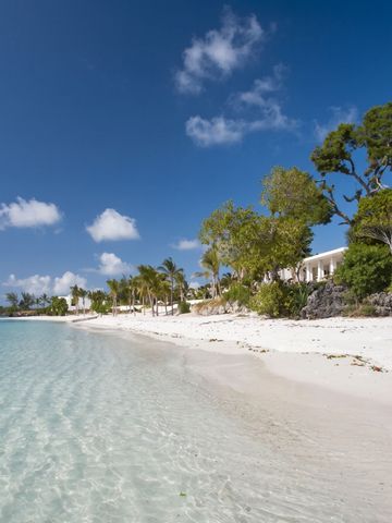 Weißer Sandstrand mit klarem Wasser und Palmen unter einem blauen Himmel