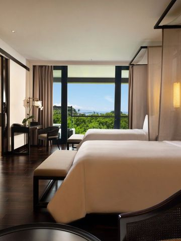 Helles Zimmer mit zwei Betten und Panoramablick auf Landschaft und Meer.