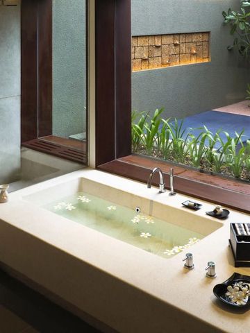 Modernes Badezimmer mit Badewanne und Gartenblick durch großes Fenster.