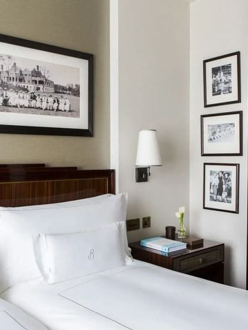 Komfortables Bett mit feiner Bettwäsche und klassischer Kunst an der Wand