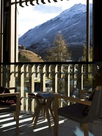 Blick von der Terrasse auf verschneite Berge und moderne Sitzmöbel