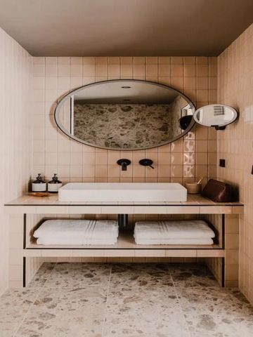 Badezimmer mit ovalem Spiegel, Waschbecken und moderner Ausstattung