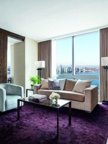Wohnzimmer einer Suite mit stilvollen Möbeln und großem Fenster mit Stadtblick