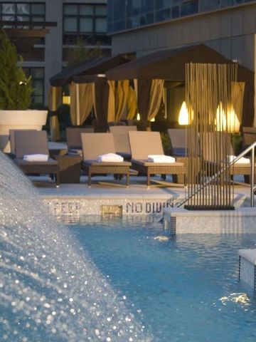 Luxuriöser Außenpool mit Wasserfall und eleganten Liegen im Hintergrund