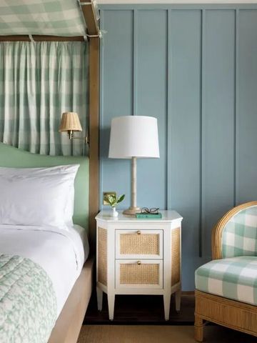 Nachttisch mit Lampe neben einem gemütlichen Bett vor einer blauen Wand