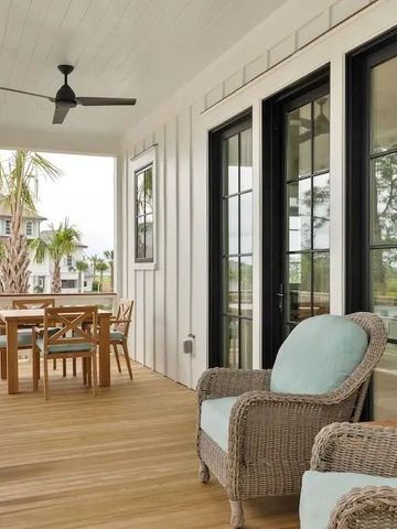 Geräumige Veranda mit Polstermöbeln und Holztisch mit Stühlen vor einer Villa