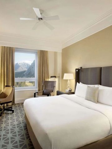 Gästezimmer mit Doppelbett und Bergblick durch ein großes Fenster