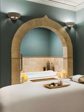 Elegantes Spa-Zimmer mit Whirlpool und geschwungenem Steinbogen