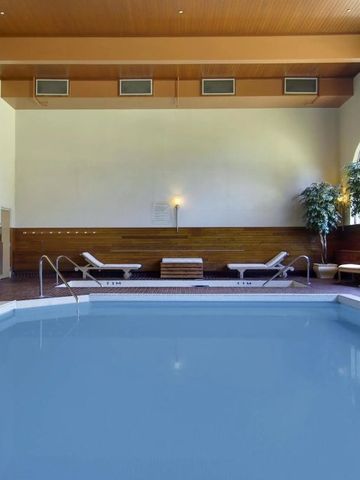 Innenpool mit Liegestühlen und Pflanzen im Hotel