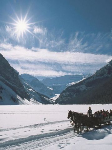 Pferdeschlitten in verschneiter Berglandschaft bei Sonnenschein