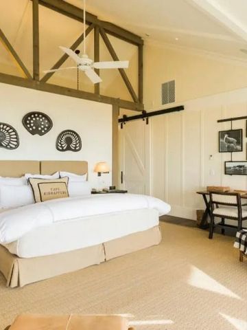 Lichtdurchflutetes Schlafzimmer mit Doppelbett, Arbeitsbereich und hohen Decken
