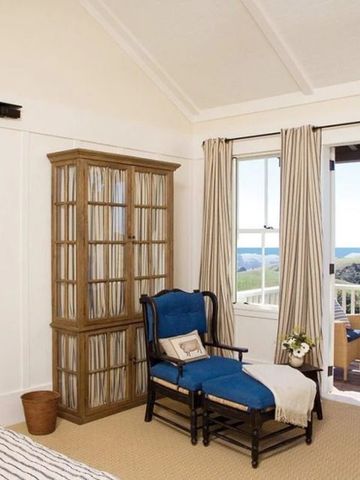 Helles Zimmer mit blauer Sessel und einem Balkon mit Meerblick