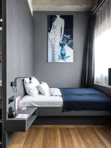 Zeitgenössisches Zimmer mit dunklen Wänden, modernem Kunstwerk und gemütlichem Bett