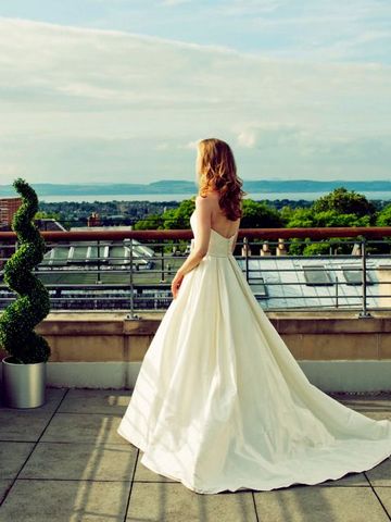 Frau im eleganten Kleid auf einer Terrasse mit Blick auf Edinburgh
